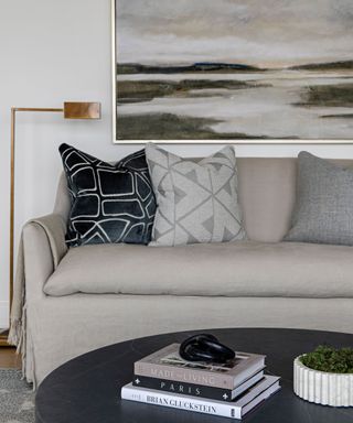 A gray couch with patterned cushions and a black circular coffee table