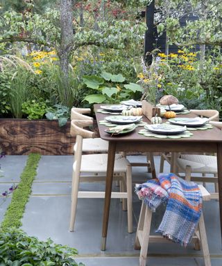 An outdoor table on a paved patio with gaps left for planting
