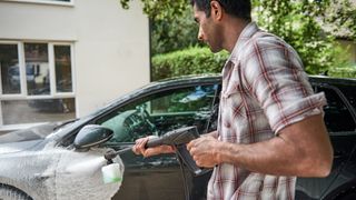 man cleaning a car using the Bosch pressure washer