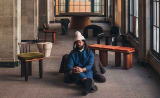 Michael Bennett sitting with his furniture designs