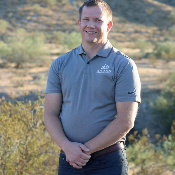 A headshot of a man in a gray shirt smiling at the camera