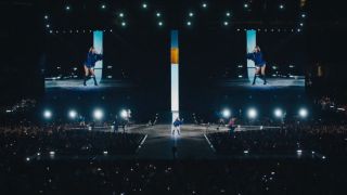 The Eras Tour stage with an orange door projected in the middle of the screen desending toward the ground.