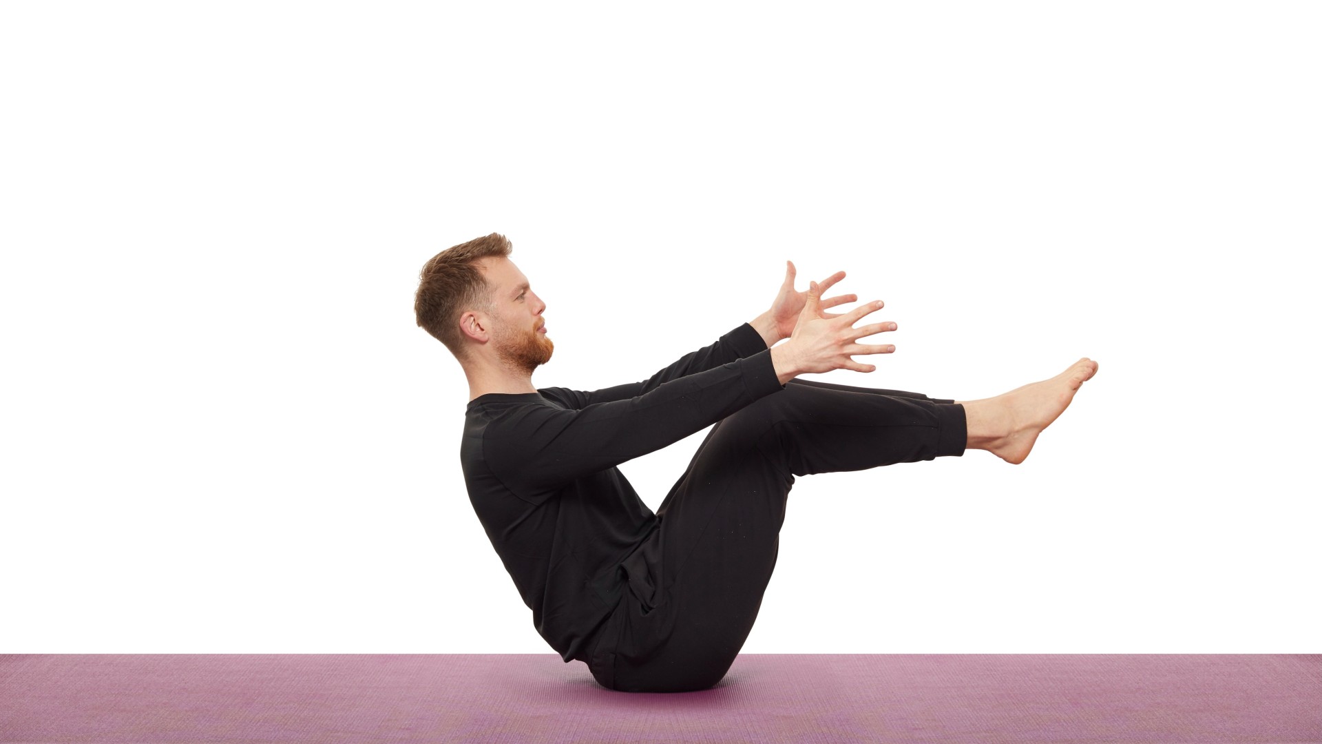 Nick Higgins demonstrating the boat pose on his yoga mat