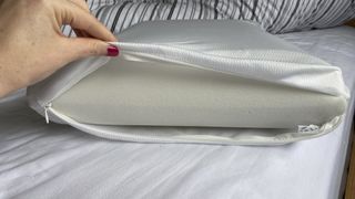 A hand holding open the Levitex Sleep Posture Pillow cover to show the foam interior