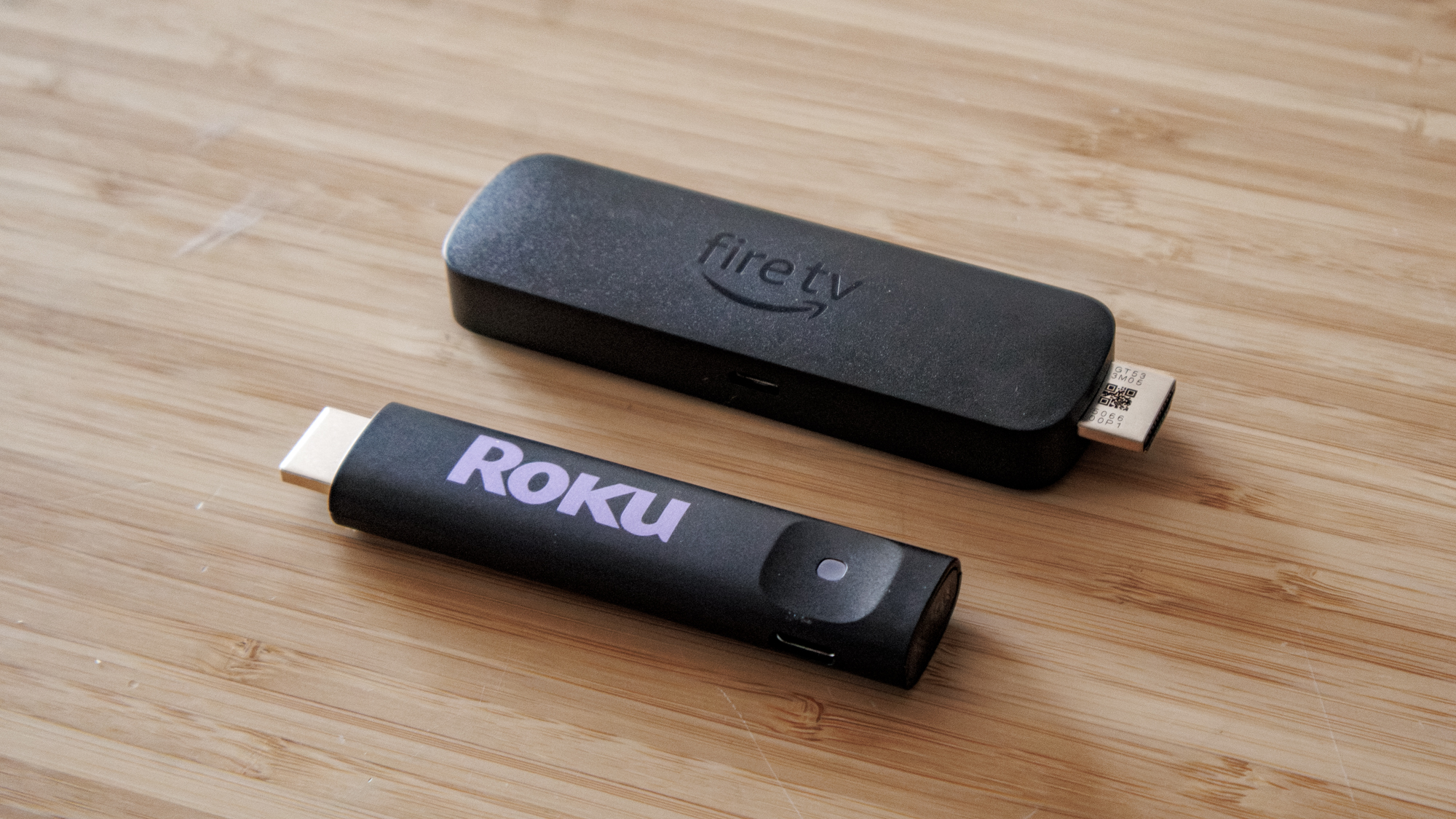 Amazon Fire TV Stick 4K Select and Roku Streaming Stick Plus on a table