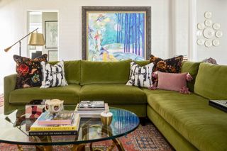 green sofa and vintage french rug in a white living room with a Hollywood Regency coffee table
