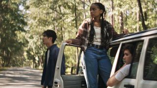 three high schoolers outside of a white jeep looking at something in the woods in a still from the movie it ends