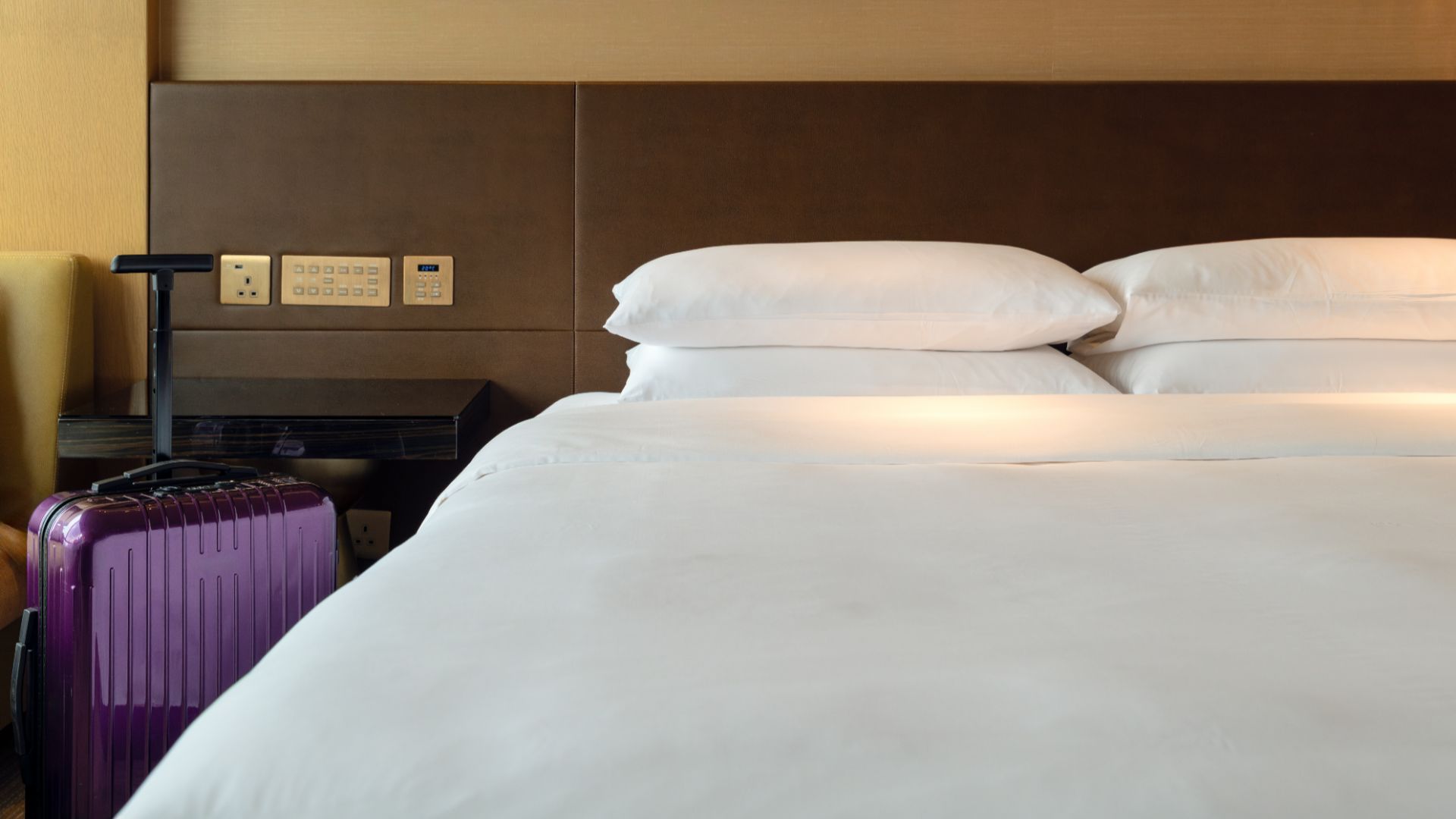 Hotel mattress with a suitcase next to it