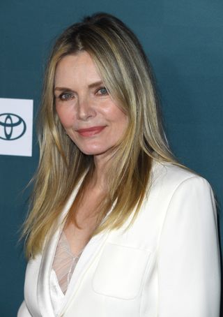 Michelle Pfeiffer wearing a white suit with layered blonde hair.