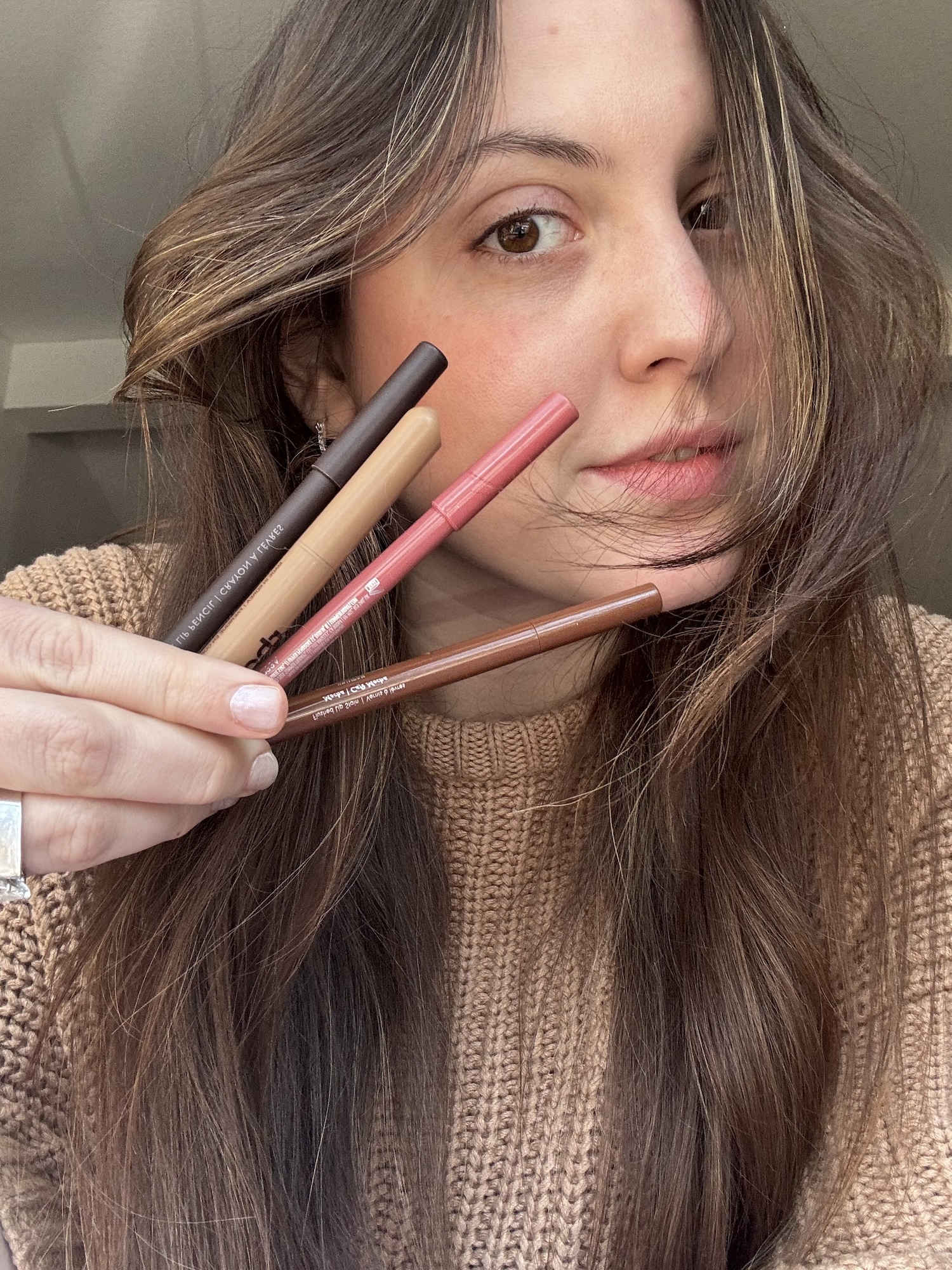 Sophia Vilensky holding a handful of nude lip liners.