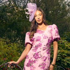 Model wearing a pink floral wedding guest dress sold at Coast