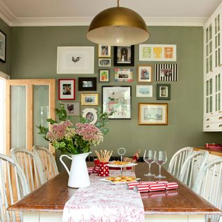 dinning room with green wall wooden dinning table with chair and frames on wall