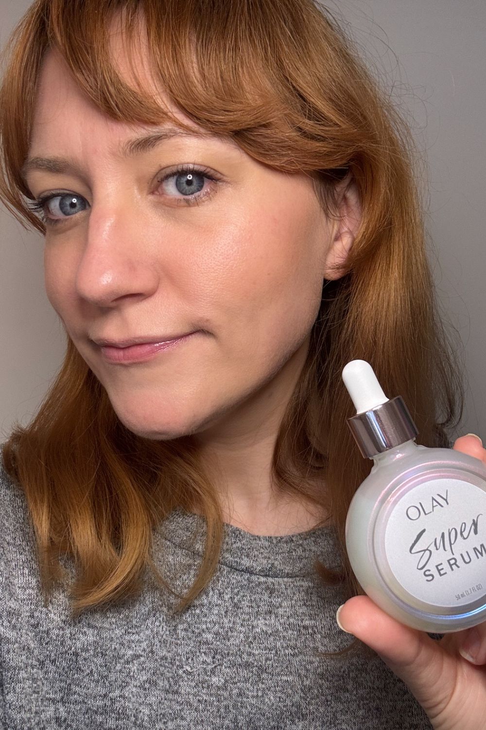 A headshot of matilda with a bottle of olay super serum