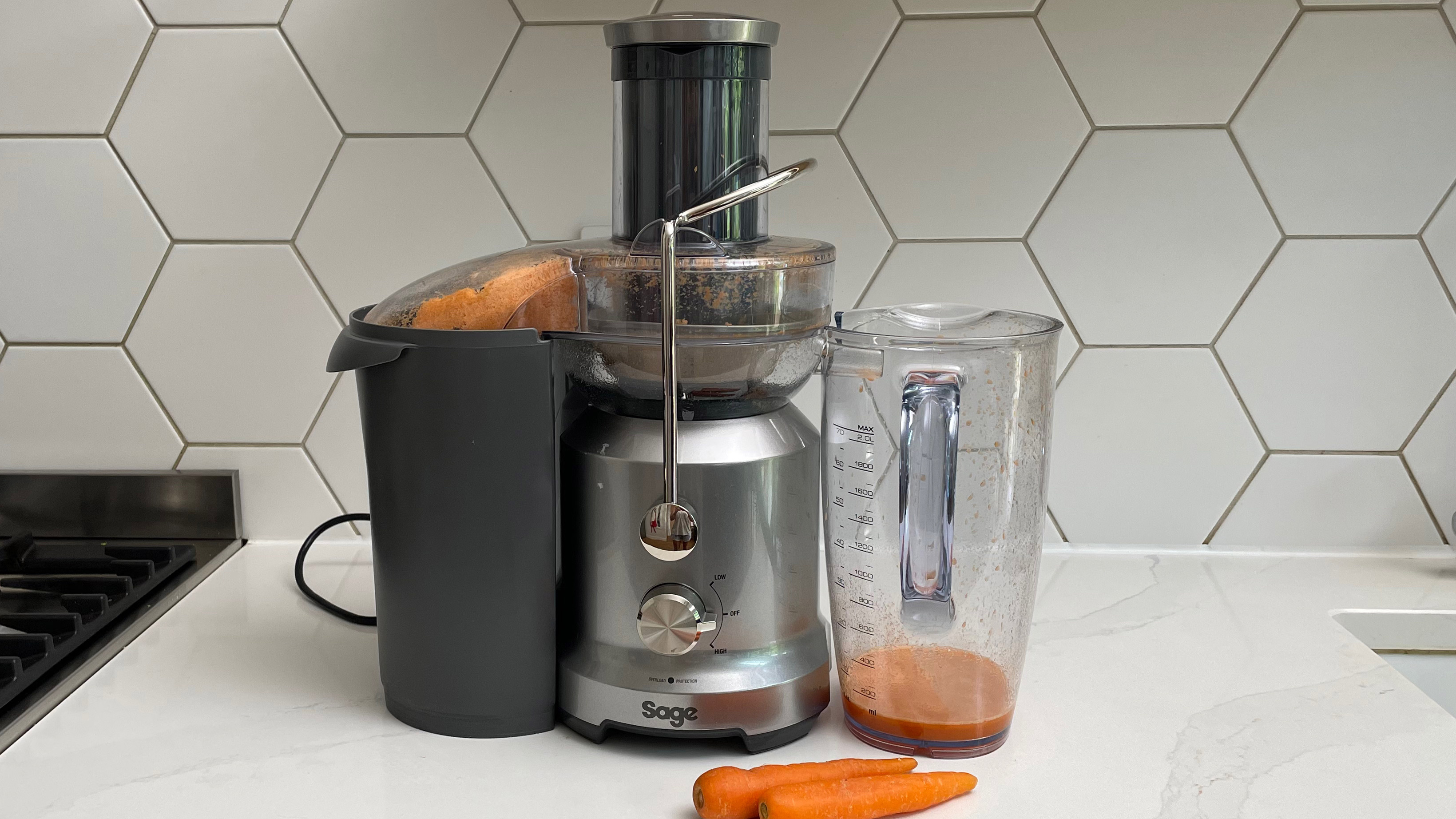 Breville the Juice Fountain Cold on a kitchen countertop filled with carrot juice