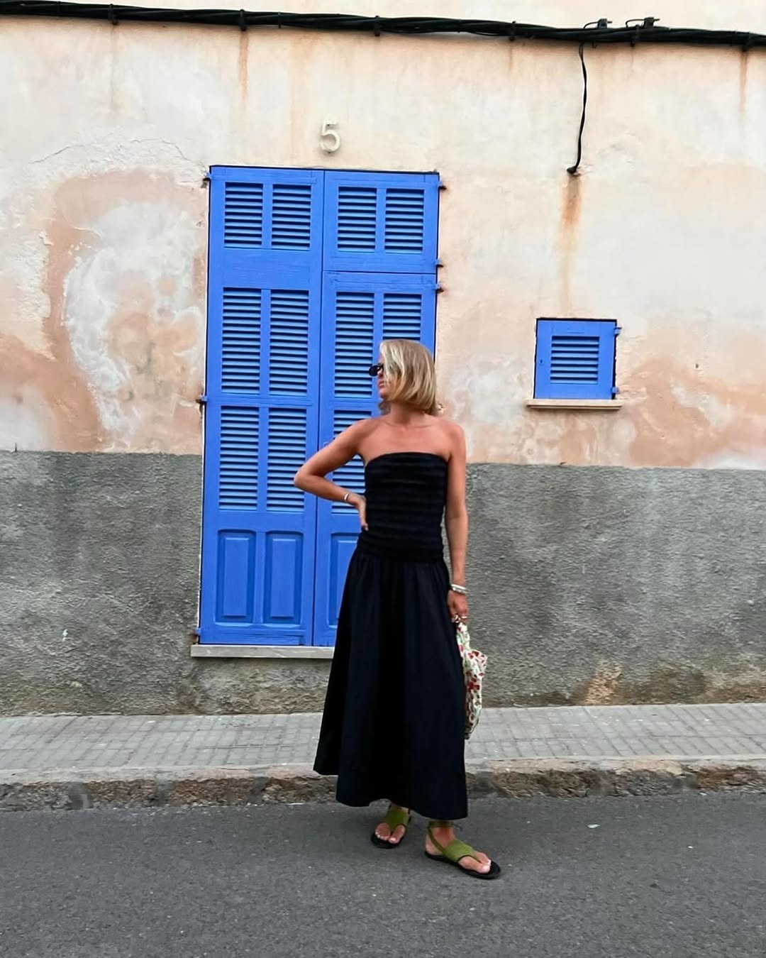 Amalie wears a strapless dress and green sandals.