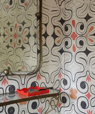 entryway with bold modern wallpaper, large iron mirror and console table with red tray with keys, Rita Konig for The Lacquer Company