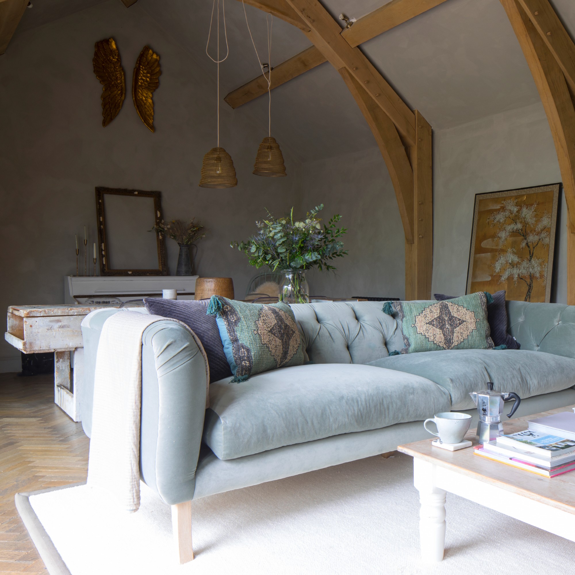 A grey living colour drenched in limewash-finish paint with a light blue velvet sofa