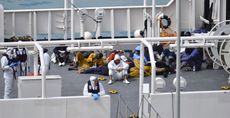 Survivors of the smuggler's boat that overturned off the coasts of Libya lie on the deck of the Italian Coast Guard ship Bruno Gregoretti.