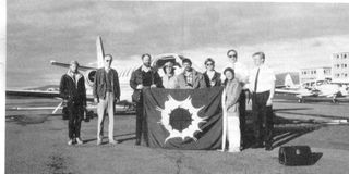 Schneider and eight other eclipse chasers in 1986. The group viewed the event from an airplane, which can be seen behind them.