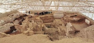 A wide view of the excavations taking place at Çatalhöyük, showing a group of people on the edge of an unearthed city