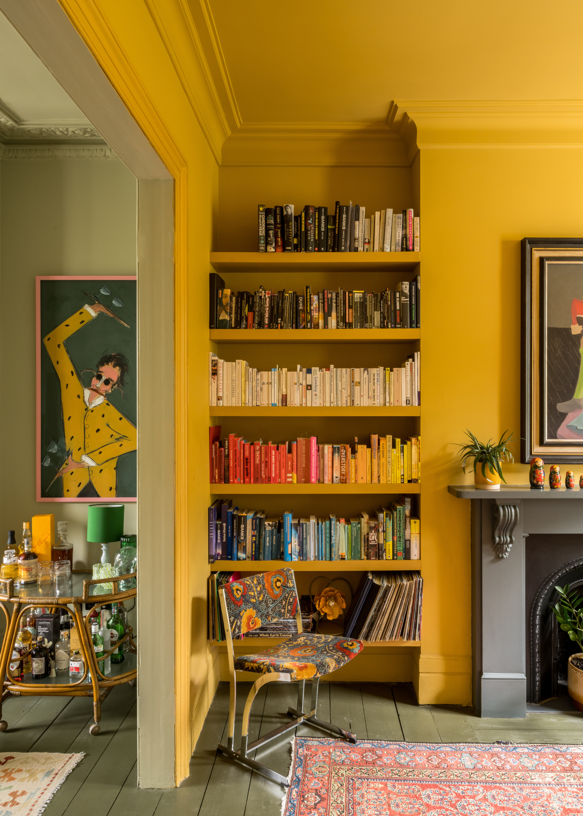 A yellow room with a color-coded bookshelf in a living room