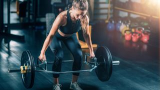 Woman performing a hex bar deadlift mid lift in a gym