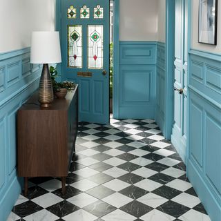 hallway with blue designed wall blue door and white and black flooring