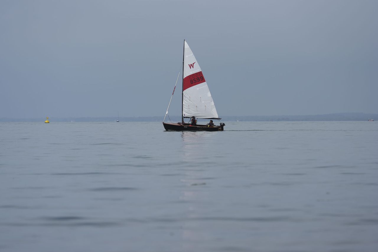 A sail boat on a still ocean at first light