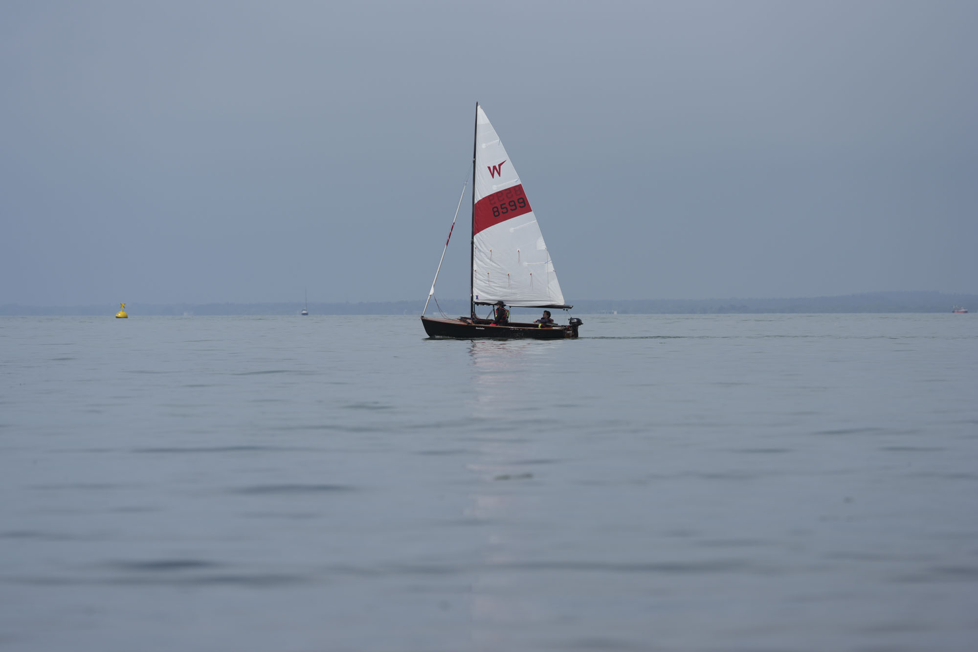 A sail boat on a still ocean at first light