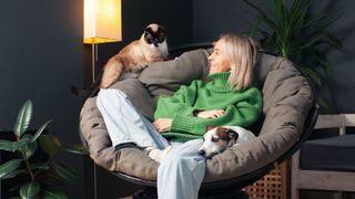 Woman in green jumper shares chair with terrier and can