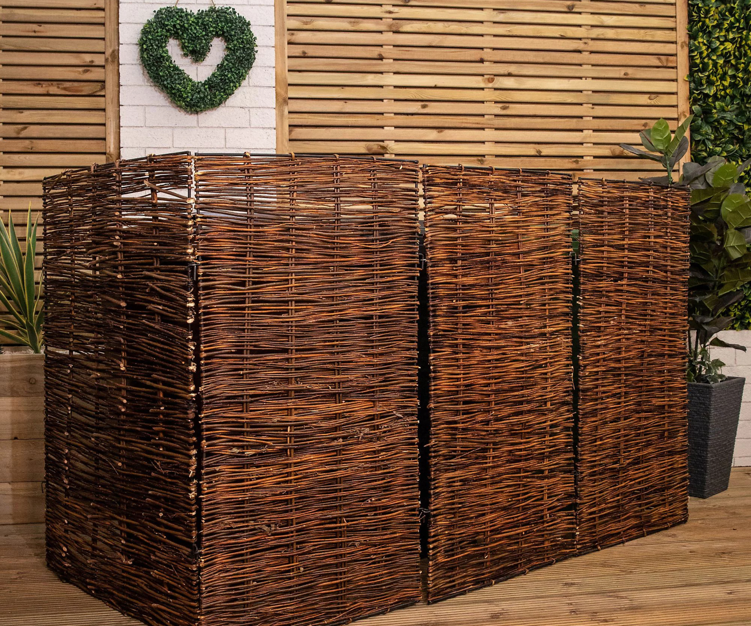 wicker wheelie bin screens, set of 3 on decking with wooden fence and white brick wall behind, green heart decor made from foliage on white wall