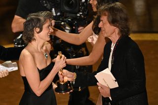 US composer Camille (L) accepts the award for Best Original Song for "El Mal" from "Emilia Perez" from British singer Mick Jagger (R) onstage during the 97th Annual Academy Awards at the Dolby Theatre in Hollywood, California on March 2, 2025.