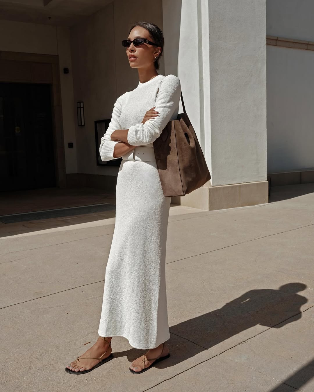 tylynn wears a white knitted maxi dress and suede sandals with a matching bag