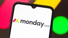 Monday.com logo and branding pictured on a smartphone screen with logo blurred in background.