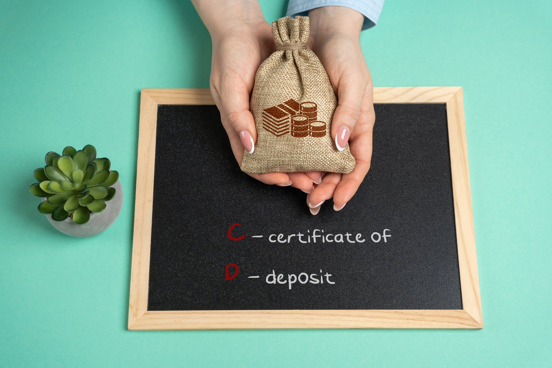 A hand holding out a burlap sack full of coins over a chalkboard reading certificate of deposit