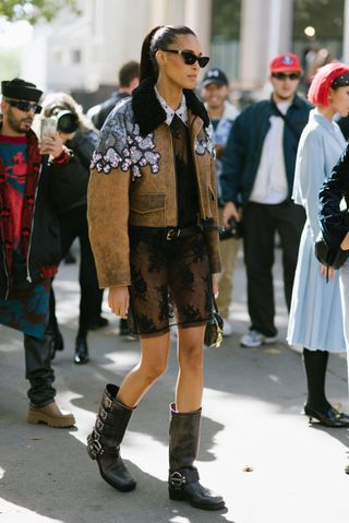 woman wearing moto boots, embellished jacket, and sheer bottoms