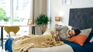 woman lying in bed with period cramps