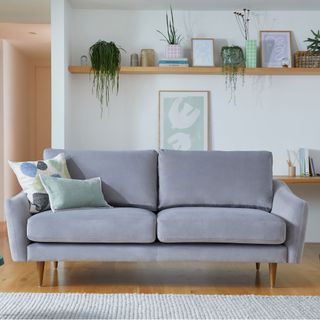 warm grey sofa in white living room with high shelf on wall behind filled with accessories snug sofa