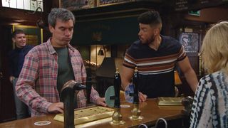 Nate Robinson and Cain Dingle at The Woolpack bar. Corey is smiling behind them as Charity Dingle pulls a pint.