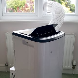 The AEG Comfort 6000 Portable Air Conditioner being tested in a room with green carpet