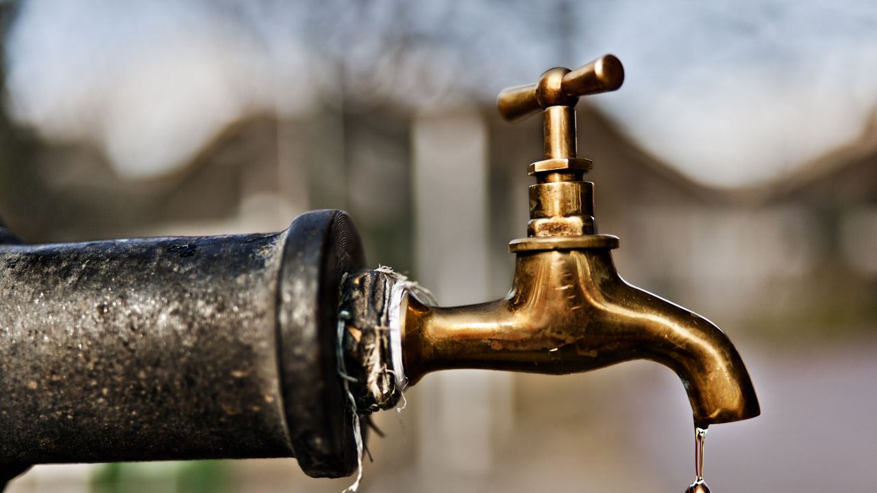 Drop of water falling from gold outside tap