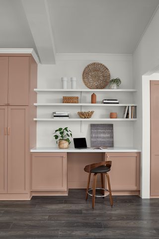 A kitchen painted in a dusky pink with white shelving