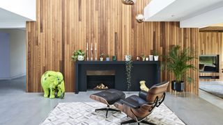 timber cladding on double height fireplace with eames chair
