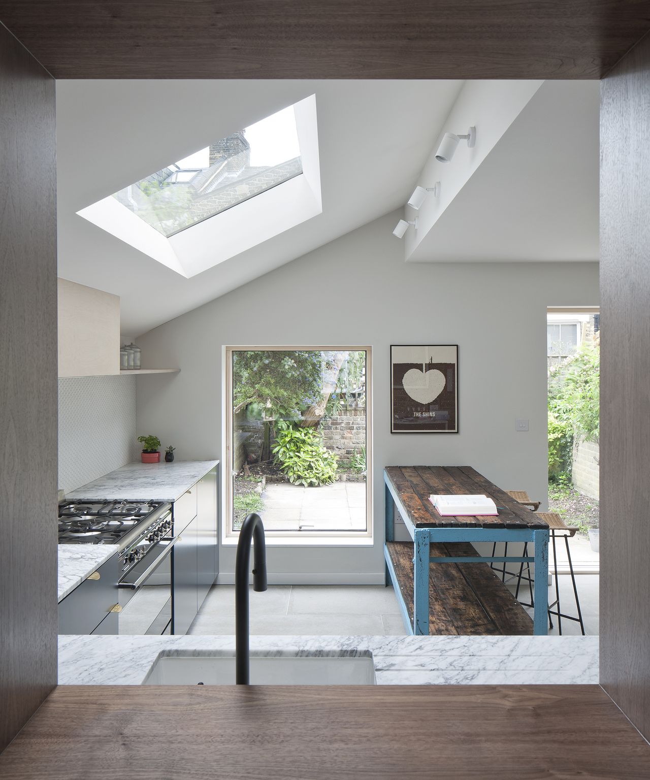 View through an internal window to a pitched roof kitchen extension with large roof light
