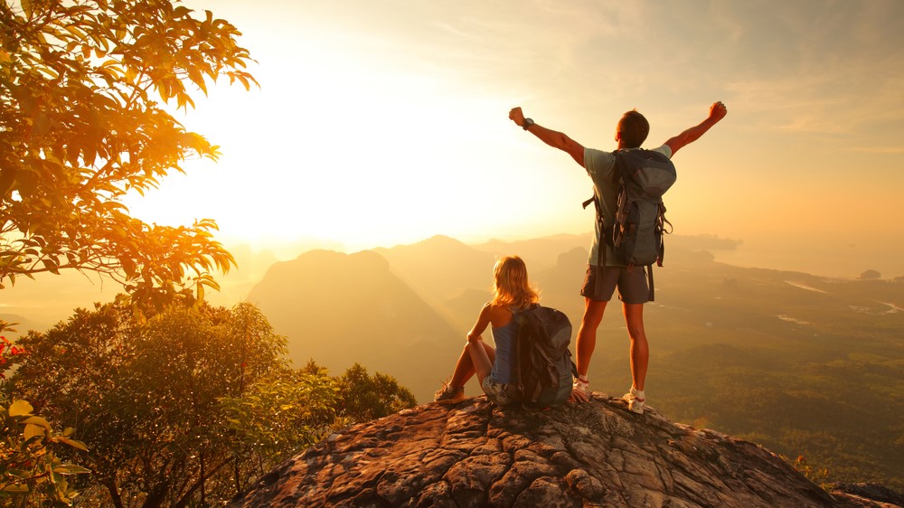 a photo of a couple hiking at sunrise