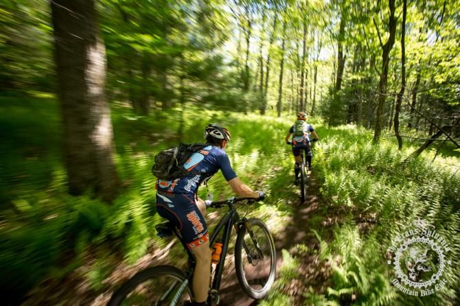 Two riders on the fern lined trails near the cam pground section of Stage 7