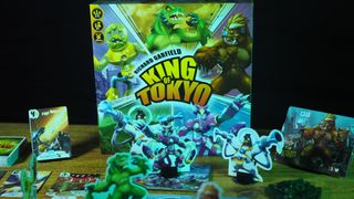 King of Tokyo components, box, and cards on a wooden table against a black background