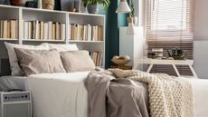A bed with a bookshelf around it and a table on it