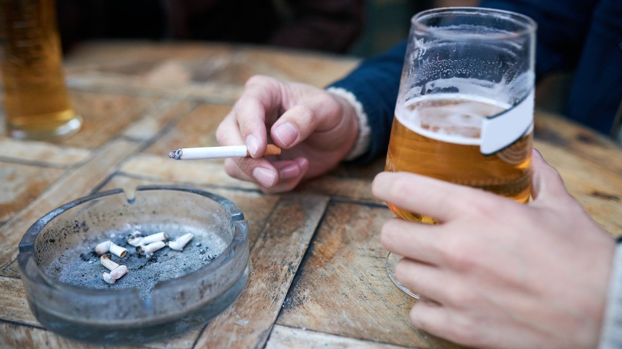 Man smoking and drinking a pint at an outdoor table