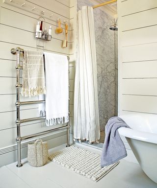 A bathroom with cream painted, horizontal wood paneled walls and a marble shower